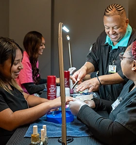 A male GTCC instructor works with three female students on nail care. 